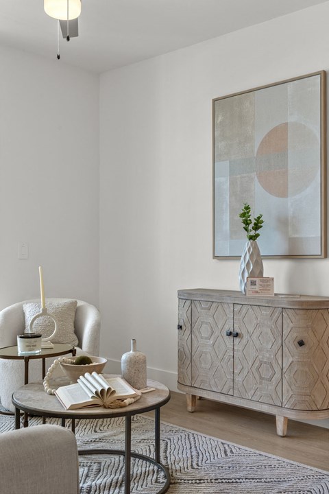 a living room with a cabinet and two chairs and a table