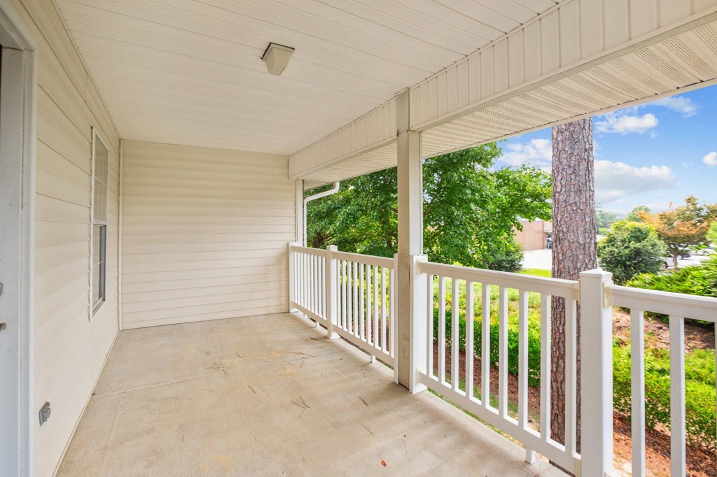 a covered porch with a view of the yard and trees