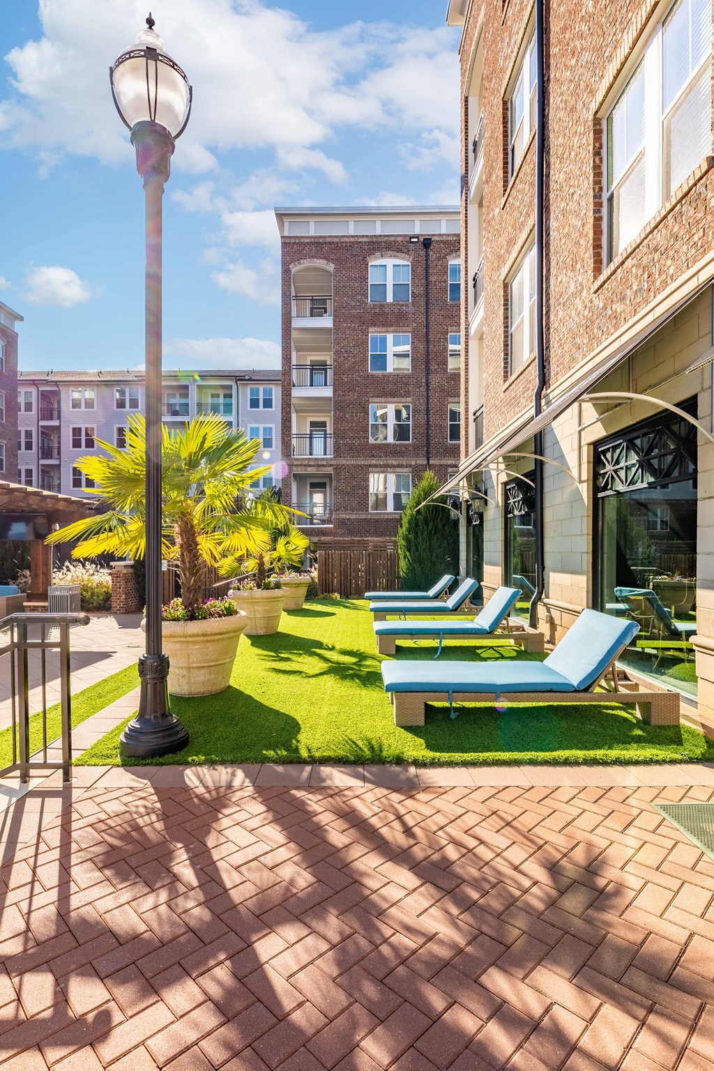 a patio with lounge chairs and a lawn in front of a building