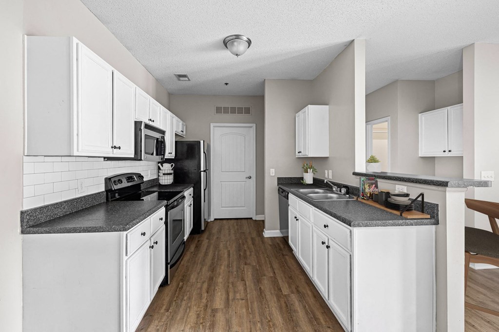 a kitchen with white cabinets and black counter tops