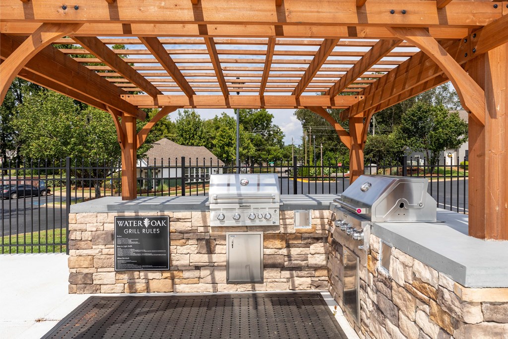 A water booth with grills and a sign that says "Grill Rules" is under a wooden pergola.