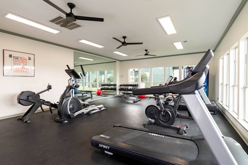 a gym with treadmills and other exercise equipment and windows