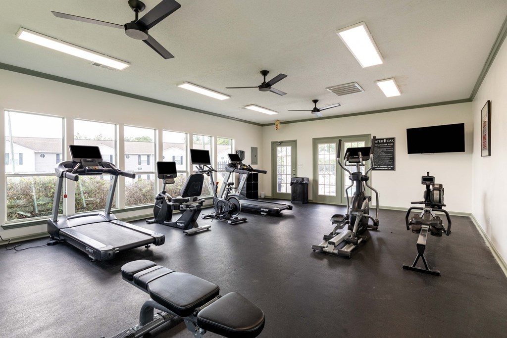 a gym with cardio equipment and windows in a building
