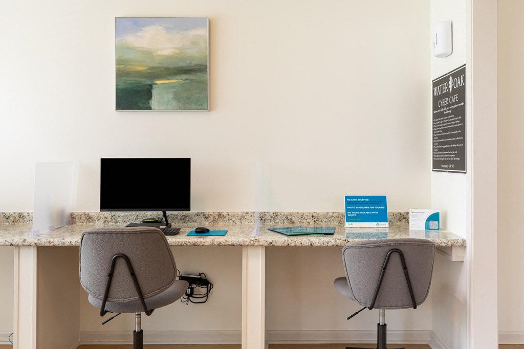 Two chairs are placed in front of two desks with a painting on the wall.
