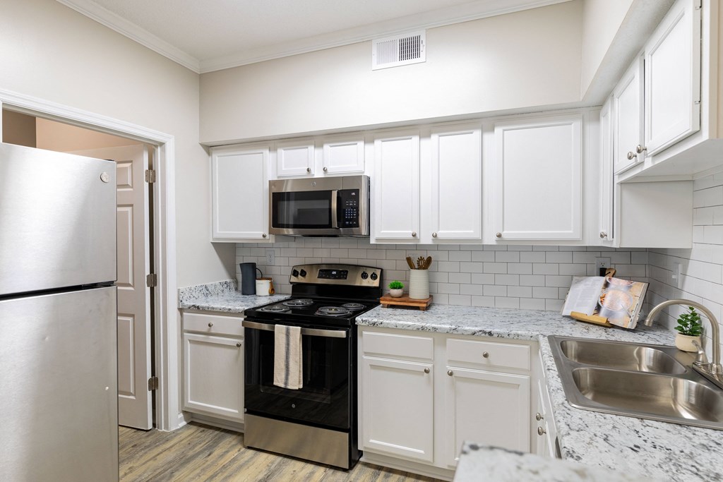 a kitchen with white cabinets and black appliances and a stainless steel refrigerator
