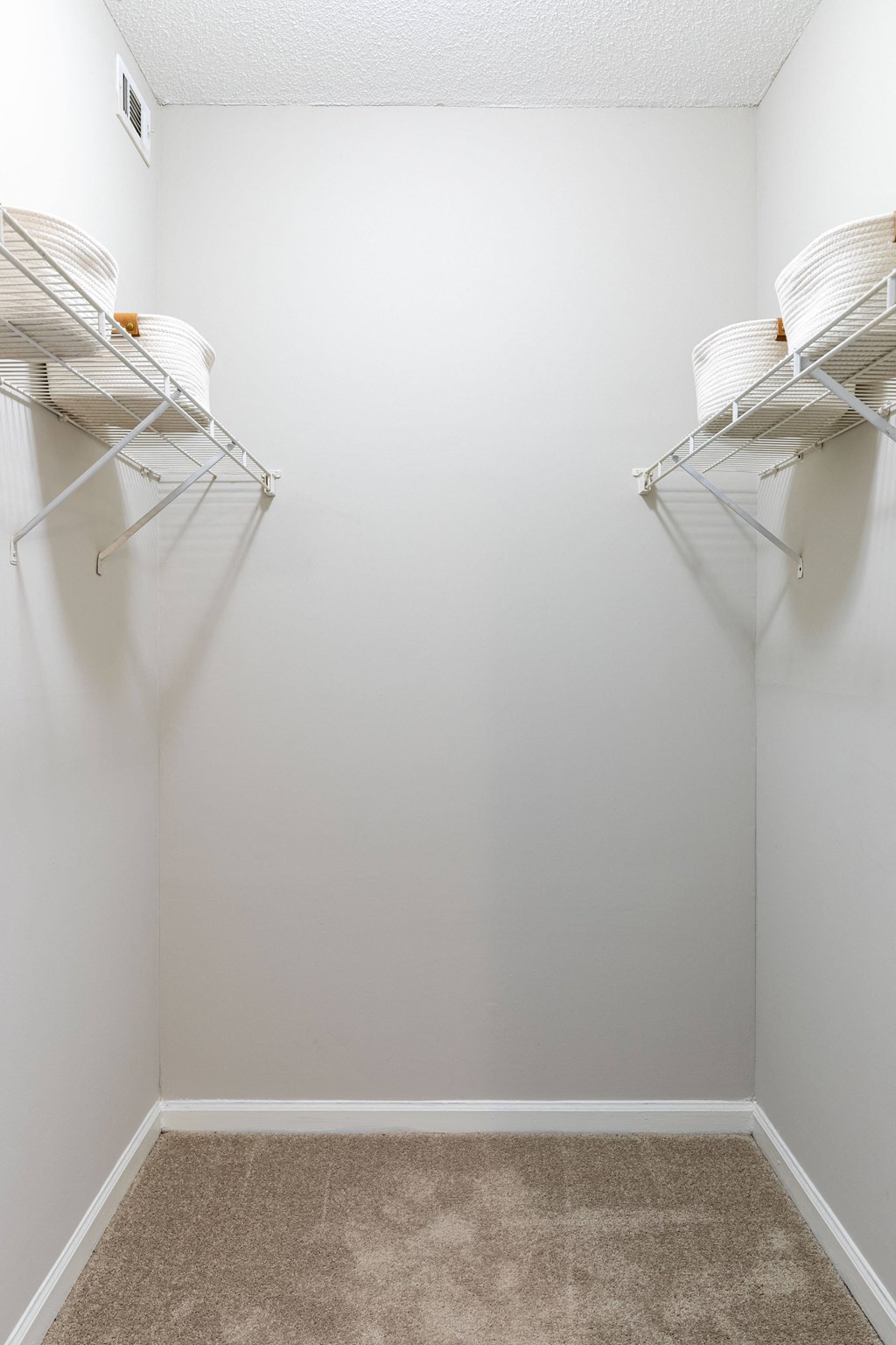 an empty room with two hanging racks on the wall and a carpeted floor