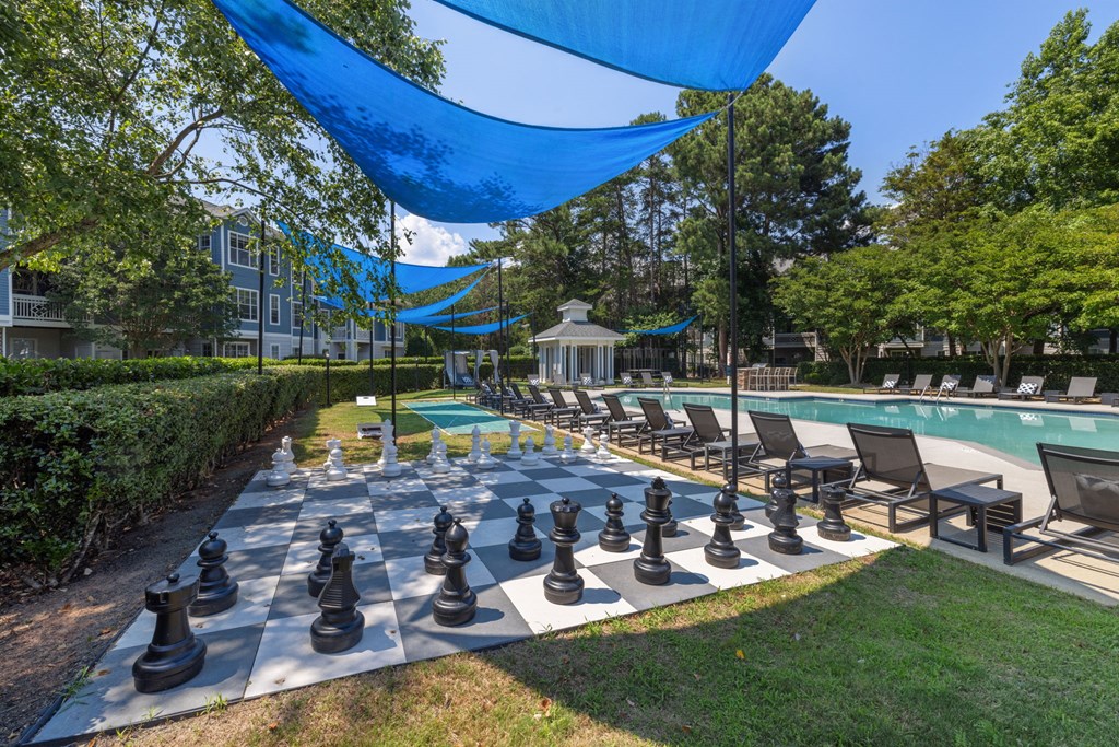a large chess board is set up next to a swimming pool