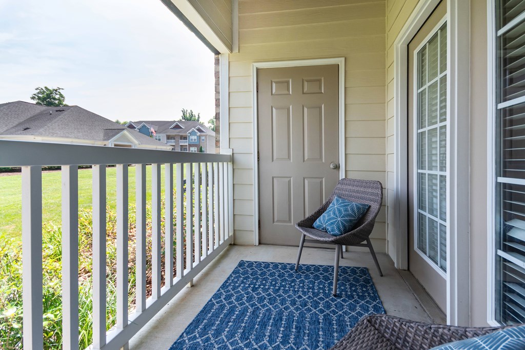 A chair with a blue pillow is on a porch.