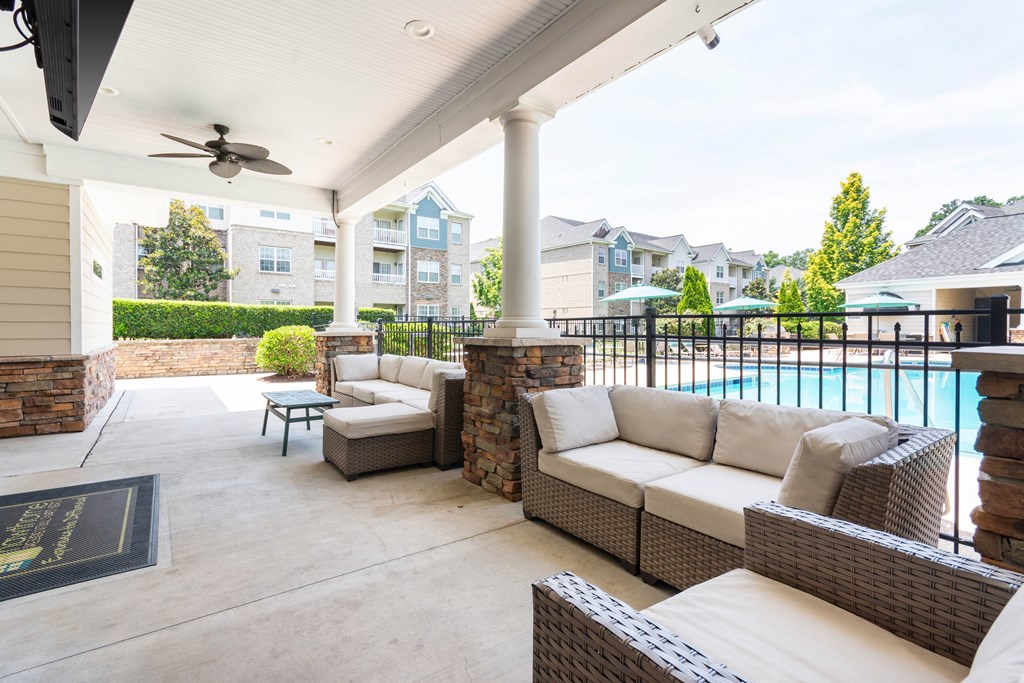 A patio with a sofa, chairs, and a pool in the background.