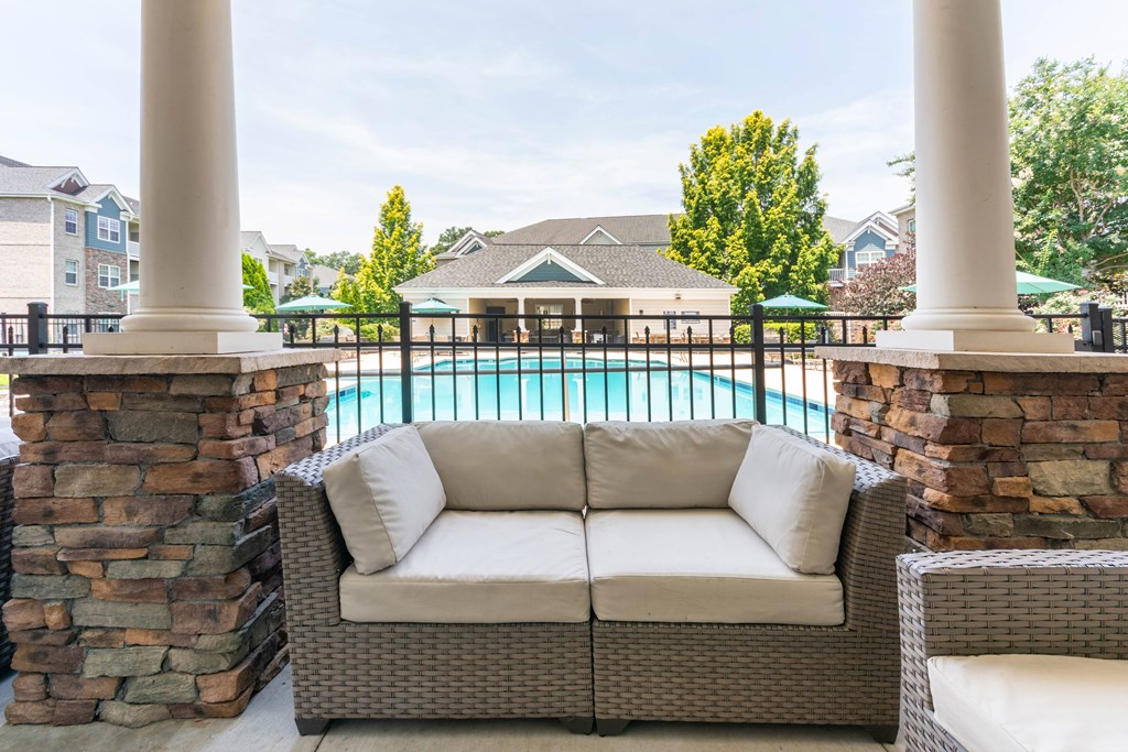 A patio with a couch and a pool in the background.
