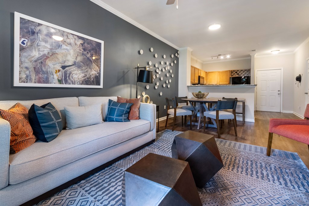 A living room with a grey couch and a large abstract painting on the wall.