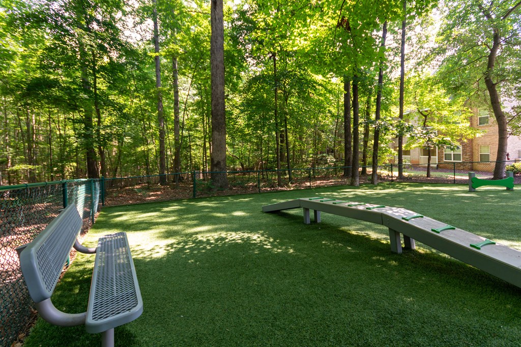 A park with a bench and a green fence.