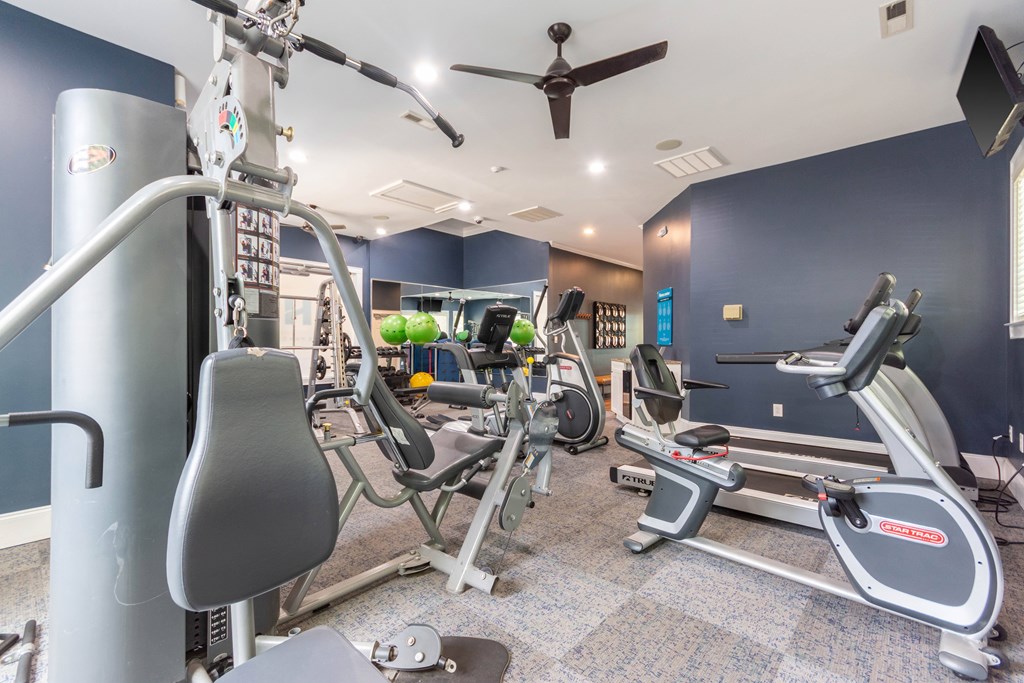 A gym with a variety of equipment including treadmills, elliptical machines, and a weight machine.