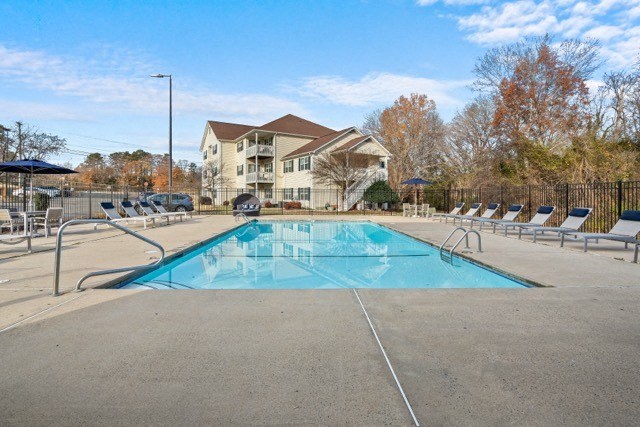a swimming pool with chairs around it in front of a house