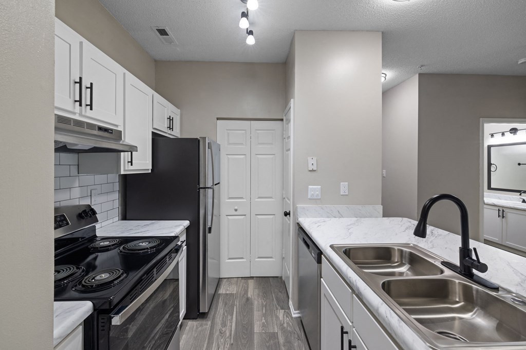 an empty kitchen with white cabinets and stainless steel appliances