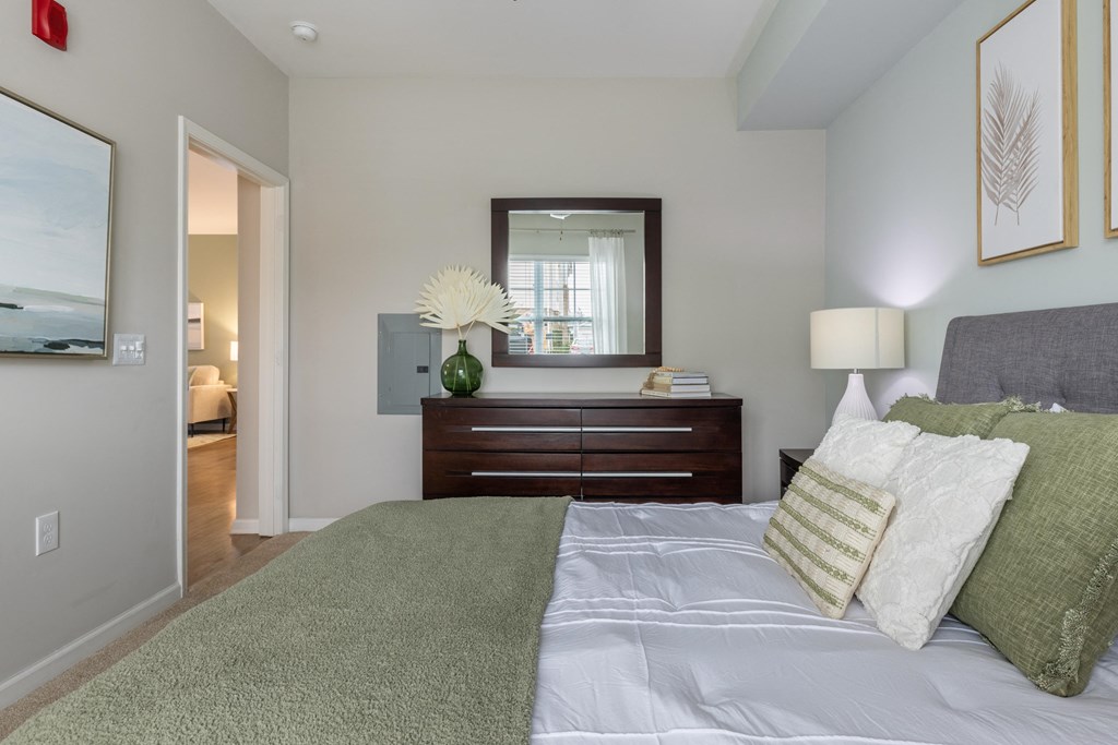 a bedroom with a bed and a dresser with a mirror