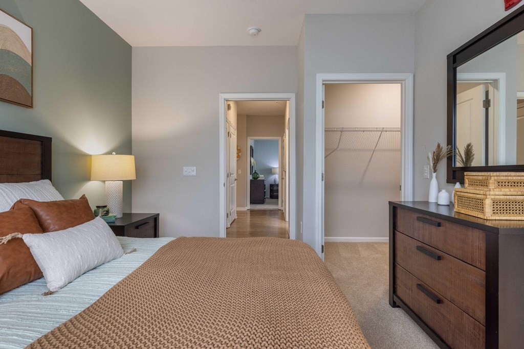 a bedroom with a large bed and a dresser and a hallway to a bathroom