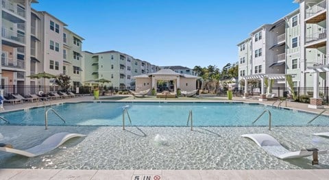 A large pool with a slide in the middle of a residential area.