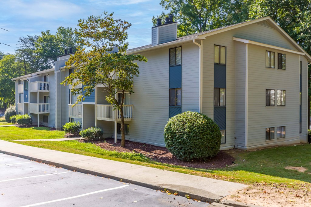 a white apartment building with a sidewalk and trees