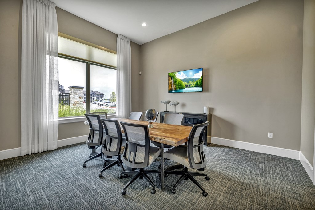 a conference room with a table and chairs and a tv on the wall