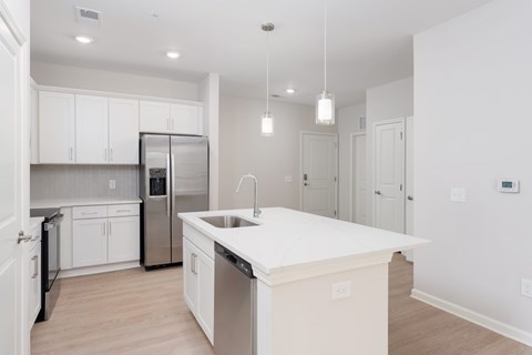 A kitchen with white cabinets and a stainless steel refrigerator at Evolve Holly Ridge Apartments in Holly Ridge, NC.