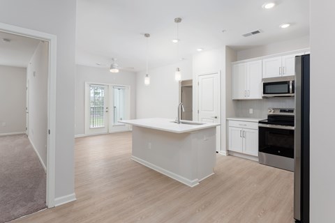 A kitchen with white cabinets and a wooden floorat Evolve Holly Ridge Apartments in Holly Ridge, NC.