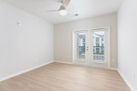 A room with a ceiling fan and a door with a window at Evolve Holly Ridge Apartments in Holly Ridge, NC.