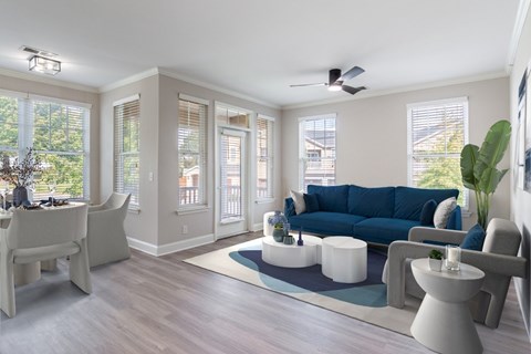A living room with a blue couch and white furniture.