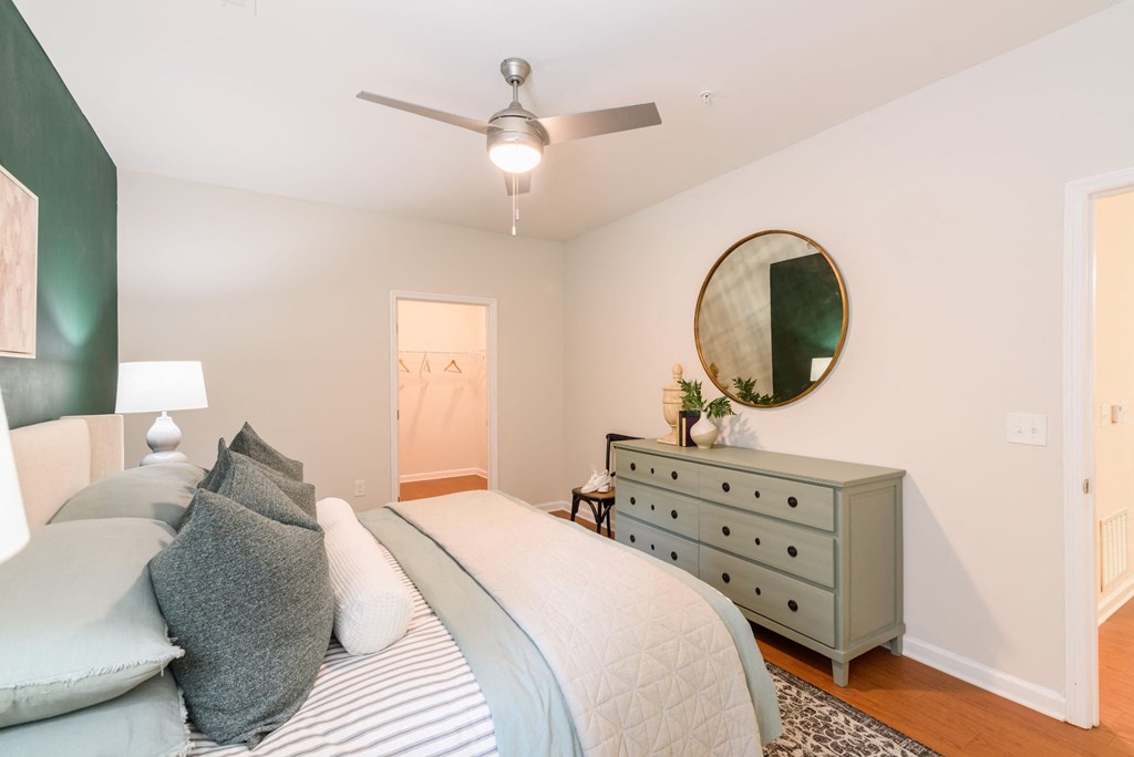 A bedroom with a bed, dresser, and mirror.