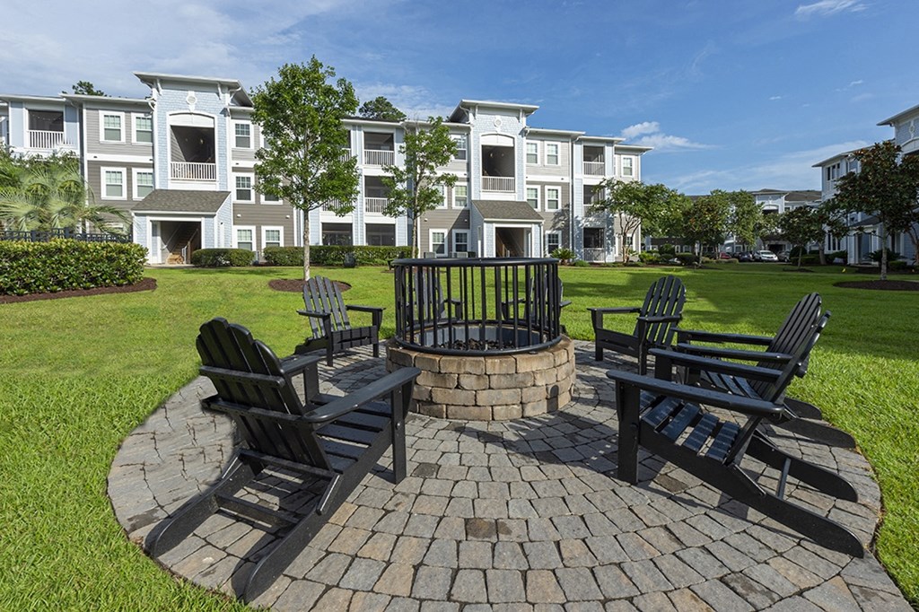 an outdoor patio with chairs and a fire pit in front of an apartment building