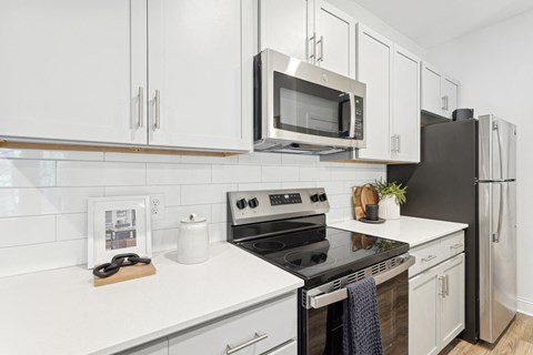 A modern kitchen with white cabinets and black appliances.