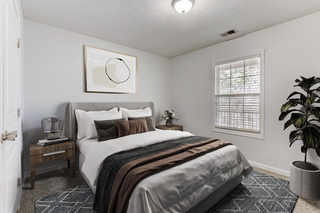 A bedroom with a bed, nightstand, and a plant.