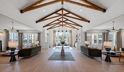 A spacious living room with wooden beams on the ceiling and a large rug in the center.