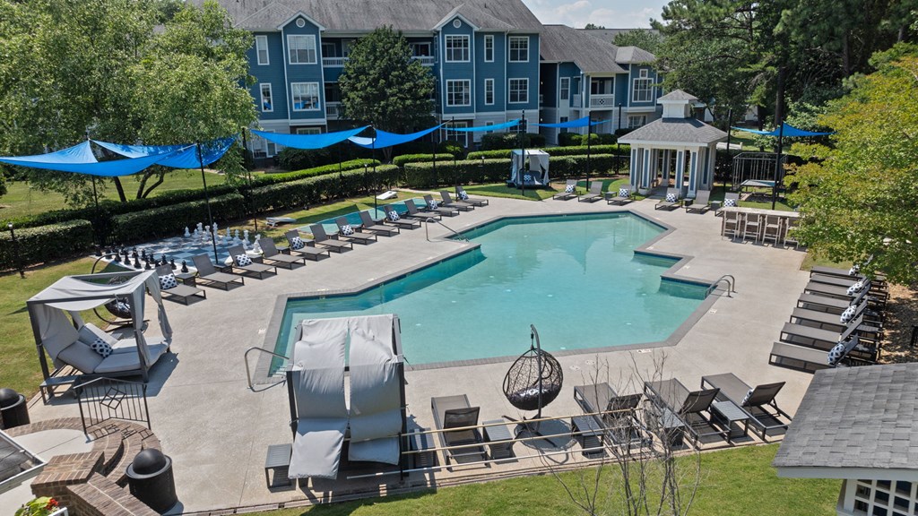 an aerial view of a resort style pool with lounge chairs and umbrellas