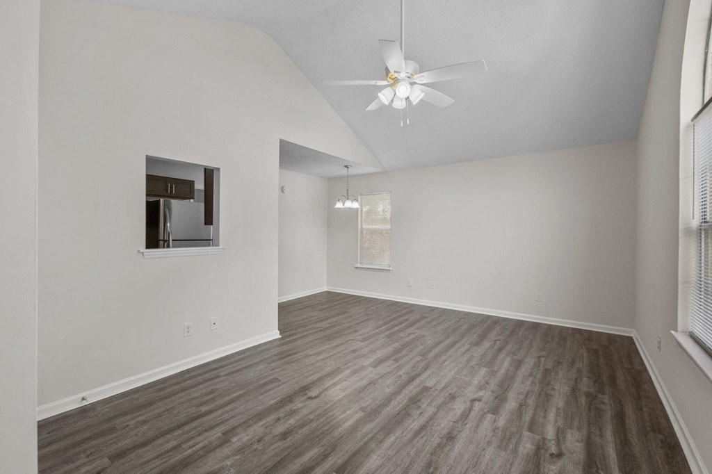 an empty living room with white walls and a ceiling fan