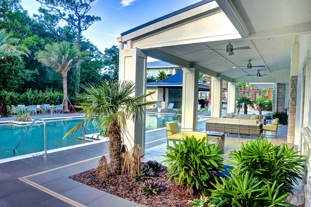 a patio with a pool and palm trees in front of a house