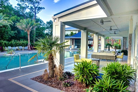a patio with a pool and palm trees in front of a house