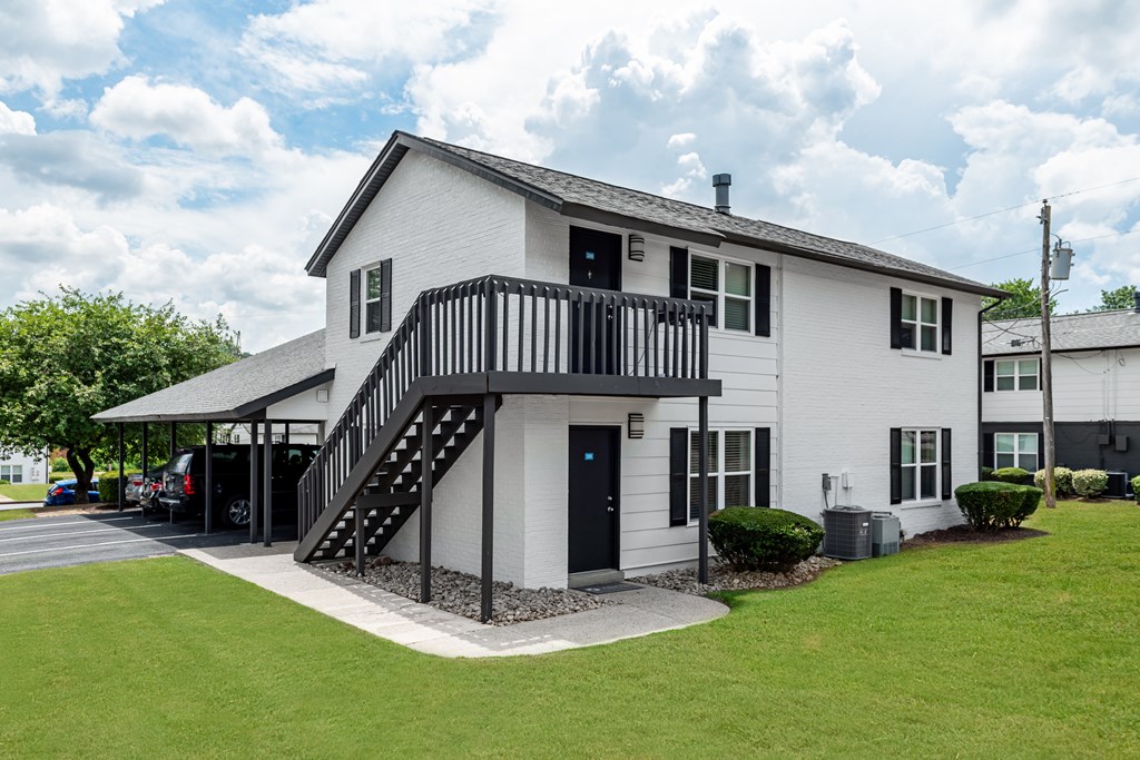 A white house with a black door and a black balcony.