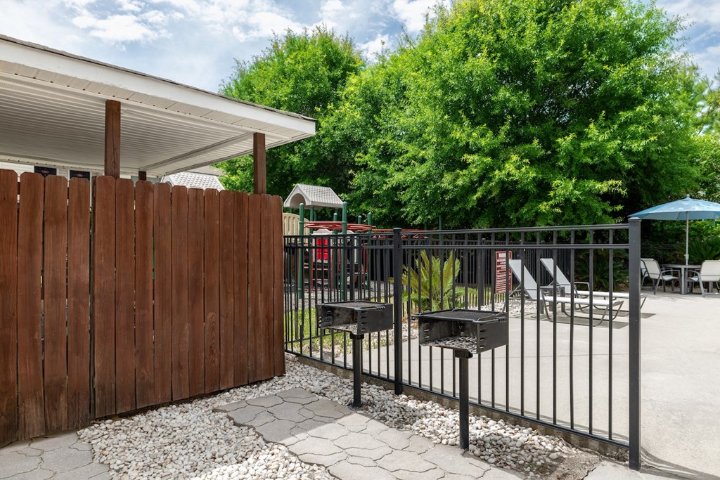 a backyard with a fence and barbecue grill