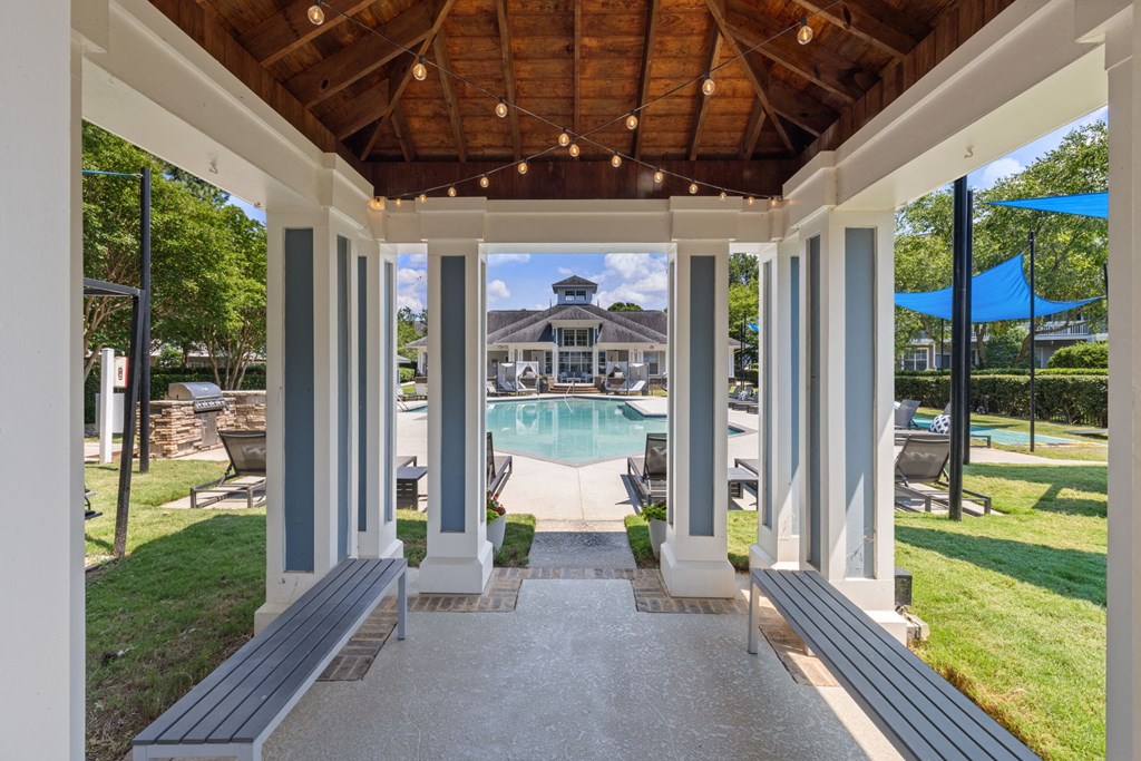 a covered porch with a pool and a house in the background