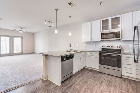 an empty kitchen with white cabinets and stainless steel appliances