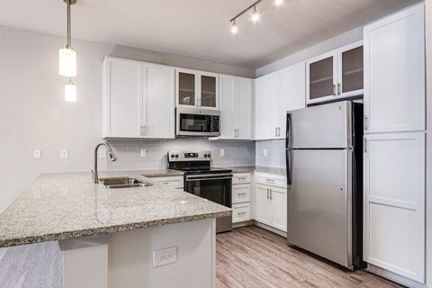 a kitchen with a granite counter top and a stainless steel refrigerator