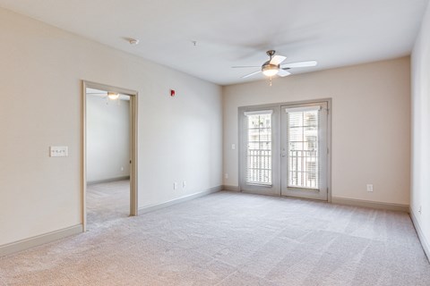 the living room and dining room of an empty house with a ceiling fan