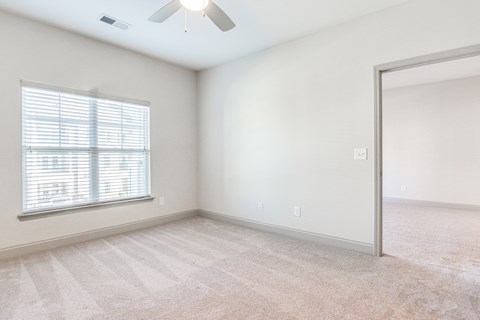 an empty living room with a window and a mirror