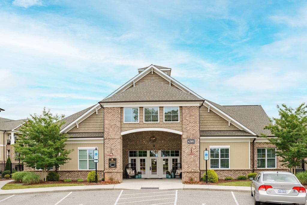 the exterior of a building with a parking lot and two cars in front