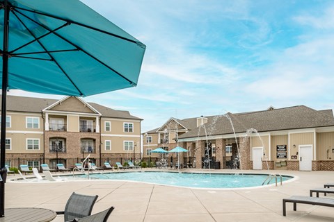 a pool with chairs and umbrellas in front of a building