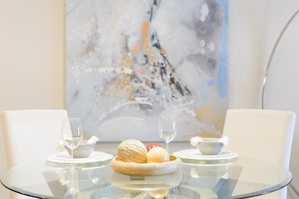 a glass table with a bowl of eggs on it and a painting in the background