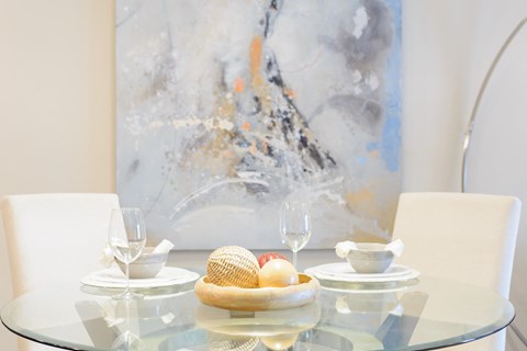 a glass table with a bowl of eggs on it and a painting in the background
