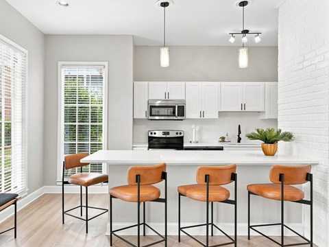 A kitchen with a white counter and orange bar stools.