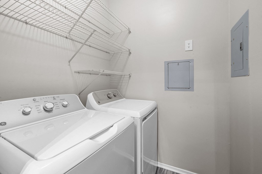 a washer and dryer in a laundry room with a shelf on the wall